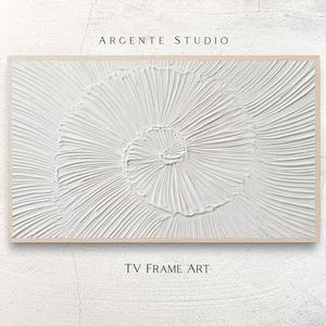 May include: White textured wall art with a spiral design, framed in a light wood. The artwork features the text "ARGENTE STUDIO" at the top and "TV FRAME ART" at the bottom.
