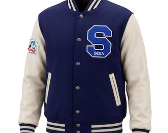 May include: A navy blue varsity jacket with cream-colored sleeves, featuring a large blue letter S with the word SEGA on the chest. The right sleeve has a circular Sonic the Hedgehog patch. It includes a striped collar, cuffs, and hem with snap buttons.