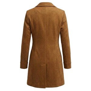 May include: A tan suede-textured coat shown from the back, featuring a structured collar, long sleeves with cuffs, and a vertical centre seam that extends down to a single vent at the hem, creating a tailored silhouette with clean lines.
