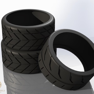 Op de afbeelding: Vier zwarte rubberen bandringen met een profielpatroon zijn gestapeld, met één los. De banden hebben een glanzende afwerking tegen een witte achtergrond. Het logo "LOW TO MOBILE - EST. 2020" staat linksonder.