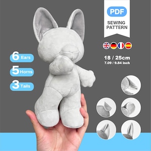 Op de afbeelding: Een PDF-naaipatroon voor een grijs pluche dier met 6 oren, 5 hoorns en 3 staarten. Het eindproduct meet 18 / 25 cm of 7,09 / 9,84 inch. De afbeelding toont het pluche wezen en ronde inzetstukken met verschillende stijlen oren.
