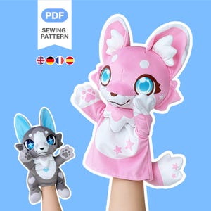 May include: Two plush hand puppets, one pink and one grey, with cartoon fox-like features. The pink puppet has large blue eyes and white accents. The grey puppet has blue ears and a white chest. The image includes text that says "PDF SEWING PATTERN".