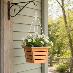 May include: A square wooden planter with horizontal slats, suspended by four white ropes from a black metal wall-mounted bracket. The planter is filled with a lush arrangement of white petunia flowers and green foliage, creating a hanging display.