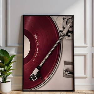 Vintage record player wall art featuring a deep burgundy vinyl record, silver tonearm and needle, turntable details, and the phrase “How Lucky Are We” on the record, with a minimalist neutral background.