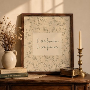 May include: A framed wall art piece featuring a cream-colored center with the text I see london I see france in black script, surrounded by a green botanical pattern on a beige background, all enclosed in a dark brown wooden frame.