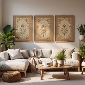 May include: Three rectangular framed wall art prints featuring intricate floral motifs in muted red, green, and gold tones on a cream background. Each print is enclosed in a simple wooden frame, displayed in a horizontal row on a plain wall.