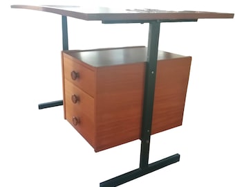 May include: A mid-century modern desk with a dark wood finish. The desk features a rectangular tabletop supported by black metal legs and a cabinet with three drawers. The drawers have round wooden knobs.