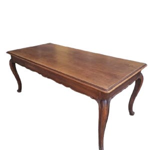 Puede incluir: Una mesa de centro rectangular de madera con acabado marrón oscuro. La mesa tiene un borde festoneado y patas curvas. La mesa mide aproximadamente 122 cm de largo y 61 cm de ancho.