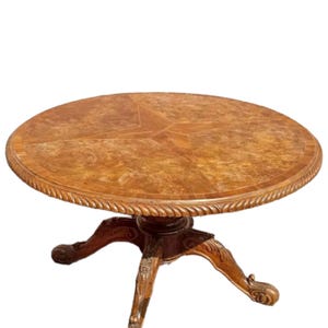 Puede incluir: Una mesa redonda de madera con un diseño de estrella en la parte superior. La mesa tiene un borde decorativo de cuerda y descansa sobre una base de pedestal con tres patas ornamentadas. La mesa mide unos 91 cm de diámetro.