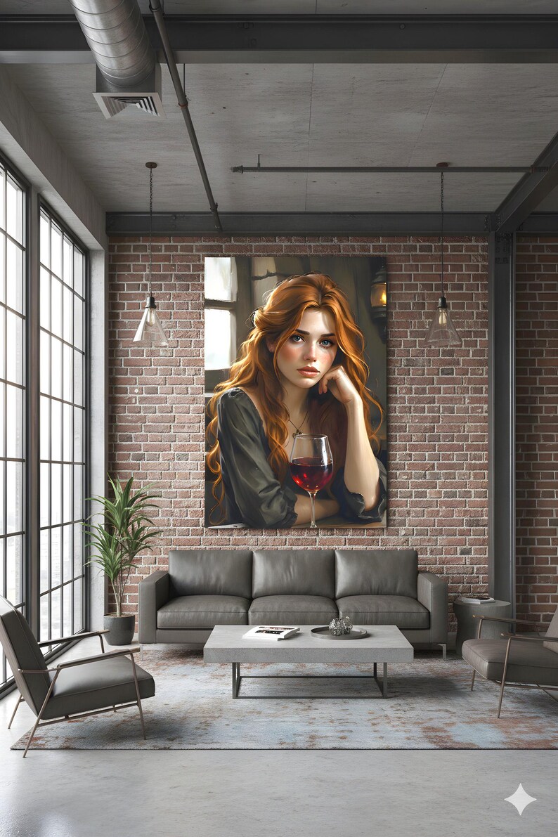 May include: A framed canvas print depicting a woman with red hair and a glass of red wine. The artwork is displayed on a brick wall above a grey sofa in a modern living room. The room has large windows and industrial-style lighting fixtures.
