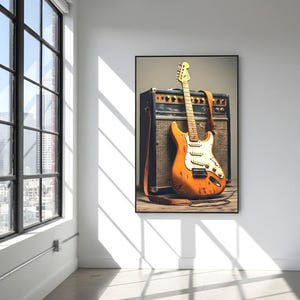 May include: An orange electric guitar with a white pickguard and a brown leather strap leans against a black and brown amplifier. The guitar has a worn appearance. The image is framed and hangs on a white wall.