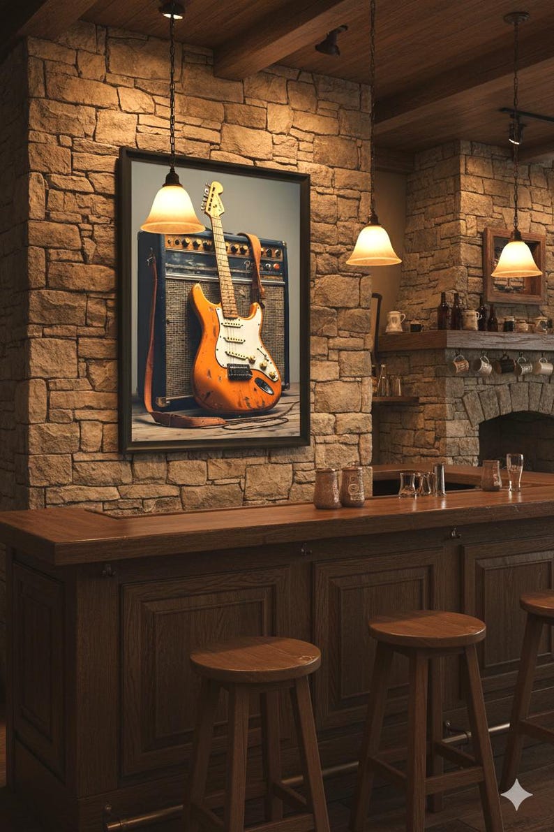 May include: A framed print of an orange electric guitar with a white pickguard and a brown strap, leaning against a vintage amplifier. The image is displayed in a rustic bar setting with stone walls and wooden furniture.