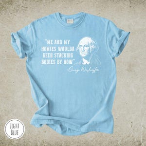 May include: Light blue t-shirt with the quote "ME AND MY HOMIES WOULDA BEEN STACKING BODIES BY NOW" and a portrait of George Washington. The text and portrait are in white. The shirt is light blue.