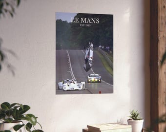 Puede incluir: Un póster con una imagen dramática de un coche de carreras volcado en una pista. El póster tiene el texto "LE MANS EST. 1923" en la parte superior. La imagen muestra otros coches de carreras en la pista y una línea de árboles verdes en el fondo.