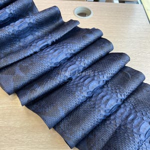 May include: A white ceramic mug with a black handle and the text "But First, Coffee" in a bold, black font. The mug is set against a blurred background, suggesting a cosy setting.