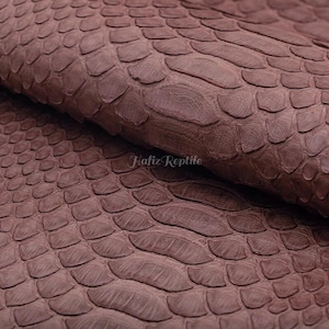 May include: Close-up of brown reptile skin with a scale pattern. The leather has a textured surface and a natural appearance. The text "Hafiz Reptile" is visible in the lower right corner.