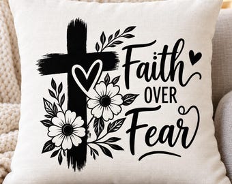May include: A square off-white throw pillow featuring a black graphic print of a cross adorned with flowers and a heart. The text "Faith OVER Fear" is printed in a black script and sans-serif font to the right of the cross design.