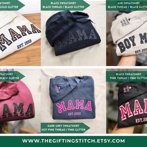 May include: A collection of sweatshirts with embroidered text. The sweatshirts are in various colors, including sand, black, ash, maroon, and dark grey. The word "MAMA" is embroidered on several sweatshirts, along with the year "EST. 1999", "EST. 2022", and "EST. 2017". The text "BOY MOM" and "EST. 2008" are also visible.