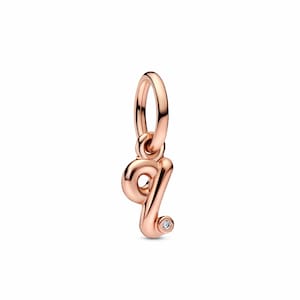 Puede incluir: Charm de color oro rosa con forma de la letra "q". El charm tiene una pequeña gema transparente en la parte inferior de la letra. El charm está suspendido de un pequeño anillo.