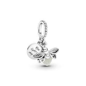 May include: A silver charm featuring a firefly design with a glowing, round body. The charm includes a small disc with the inscription "You light my". The firefly has detailed wings and is suspended from a beaded loop.