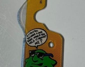 May include: A yellow and orange plastic tag with a cartoon green blob wearing sunglasses. The tag has the text "If I told you, you have a nice body, would you hold it against me?" and the number "31-1006-2011-10-SP".