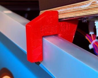 May include: Close-up of a red 3D-printed bracket with the text "FUNHOUSE" on the side, attached to a light blue and silver surface. The bracket is supporting a wooden panel with electronic components and wires.