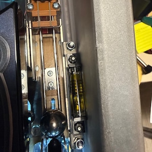 May include: Close-up of a pinball machine's interior, showcasing metallic components, a level, and a silver ball. The image includes the text "PROTEGO" and "SPELL HARD TO LIGHT". The level is filled with a yellow liquid.