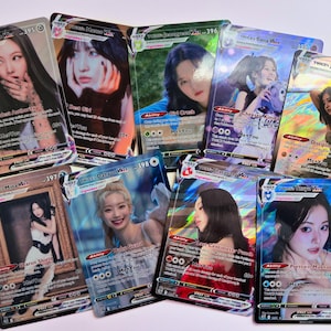 以下が含まれることがあります： K-POPグループTwiceのメンバーの画像が描かれたホログラフィックトレーディングカードのコレクション。各カードには異なるメンバーが描かれており、名前、カード番号、特殊能力などのテキストが含まれています。カードは光沢のある反射面を持っています。