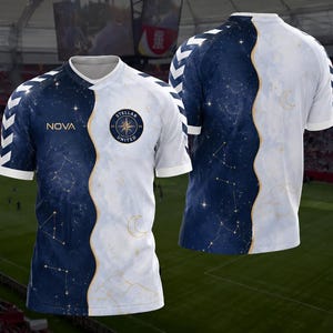 Könnte beinhalten: Ein kurzärmeliges Sporttrikot mit einem geteilten Design aus tiefem Marineblau mit goldenen Sternbildern und Weiß mit einem Halbmond. Auf der Vorderseite befinden sich der Schriftzug NOVA und ein kreisförmiges Abzeichen mit der Aufschrift STELLAR UNITED 26. Weiße Chevron-Muster säumen die Ärmel.