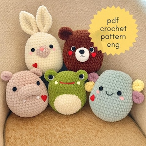 May include: Five handmade crochet animal toys: a bunny, bear, hippo, frog, and a smiling creature. Each toy has a unique design with embroidered features and heart accents. The toys are made of soft, textured yarn and are in various pastel colors.