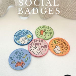 Può includere: Cinque toppe ricamate circolari etichettate PET SOCIAL BADGES. Le toppe presentano disegni colorati con cani dei cartoni animati e testo che include NEED SPACE, SOCIAL PUP, PLEASE PET ME, DO NOT PET e I'M SO SHY, ognuna con illustrazioni uniche.