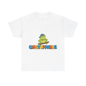 Könnte beinhalten: Weißes T-Shirt mit einem Cartoon-Frosch, der ein blaues Käppi trägt und Skateboard fährt. Das Wort "UNSTOPPABLE" steht in bunten Buchstaben darunter. Ein lustiges und verspieltes Design.