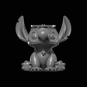 Pode incluir: Figura cinzenta impressa em 3D do personagem Stitch do filme Lilo & Stitch. A figura está sentada com orelhas grandes, um nariz grande e olhos fechados. A figura está em um fundo preto.