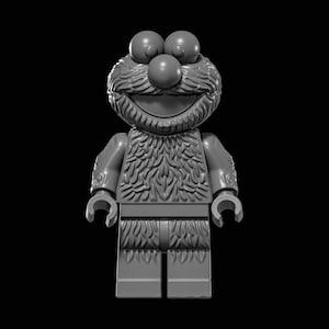 May include: A gray Lego figure of a Sesame Street character with a large, smiling mouth, a red nose, and two large eyes. The figure has a furry chest and arms, and is standing on a black background.
