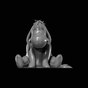 Op de afbeelding: Een grijze figuur van Eeyore, het ezelskarakter uit Winnie de Poeh, zit met uitgestrekte benen. De figuur heeft een gestikt ontwerp en een trieste uitdrukking. De achtergrond is zwart.