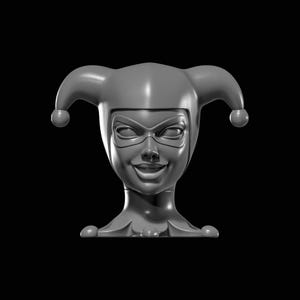 May include: A gray sculpture of a smiling jester's head, featuring a mask and a jester's hat with two rounded tips. The sculpture has a smooth, reflective surface and is set against a black background.