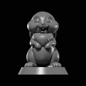 May include: A grey, cartoon-style bunny figurine with a happy expression. The bunny has large cheeks, a fluffy chest, and is standing on a rectangular base. The figurine is a 3D render against a black background.