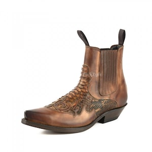 Könnte beinhalten: Braune Leder-Ankle-Boots mit spitzer Zehenpartie und Ziernähten. Der Stiefel hat ein schuppenartiges Muster auf dem Blatt und eine Zuglasche am Rücken. Der Stiefel hat einen gestapelten Absatz und eine Gummisohle.