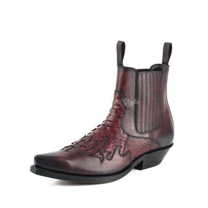 May include: A burgundy leather ankle boot with a pointed toe and a stacked heel. The boot features decorative stitching and a textured pattern on the vamp. It has pull tabs at the top and a black sole.