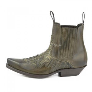 Könnte beinhalten: Olivgrüner Leder-Cowboystiefel mit spitzer Zehenpartie und Ziernähten. Der Stiefel hat ein Schlangenmuster auf dem Blatt und eine Zuglasche oben. Eine stilvolle, westlich inspirierte Schuhoption.