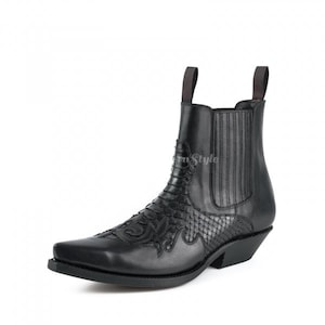 Könnte beinhalten: Schwarze Leder-Ankle-Boots mit spitzer Zehenpartie und dekorativen Nähten. Der Stiefel hat eine Zuglasche und ein strukturiertes Design auf dem Blatt. Der Absatz ist ca. 3,8 cm hoch.