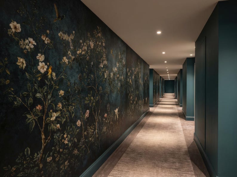 May include: A long hallway with a floral wallpaper on the left wall and teal walls on the right. The wallpaper features a dark blue background with white flowers, green leaves, and yellow birds. The floor is covered with a beige carpet.