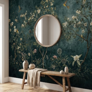 May include: A dark teal floral wallpaper with a round mirror, wooden bench, and vases. The wallpaper features white flowers, birds, and foliage. A beige throw blanket rests on the bench, and a woven rug is on the floor.