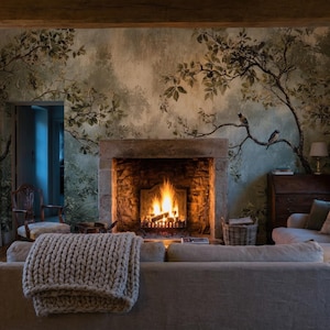 Puede incluir: Un sal&oacute;n acogedor con una chimenea encendida, un sof&aacute; gris y una gran manta de punto. La habitaci&oacute;n presenta un mural de &aacute;rboles y ramas en la pared, creando un ambiente c&aacute;lido. Tambi&eacute;n se ven un mueble de madera y una ventana.