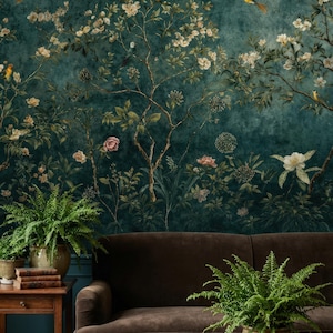 Könnte beinhalten: Eine dunkelblaue florale Tapete mit blühenden Bäumen, Vögeln und Blättern. Vor der Tapete befinden sich ein braunes Samtsofa und ein hölzerner Beistelltisch mit Büchern und Topffarnen. Das Gesamtthema ist Natur und Wohnkultur.