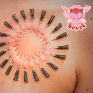 May include: A close-up of skin with multiple needles and syringes arranged in a circular pattern. The skin is reddish, and the needles are dark brown. A pink and white "little bevel" sticker is in the upper right corner.