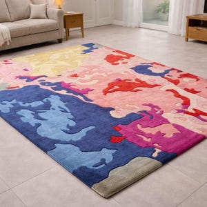 May include: A large, rectangular area rug with an abstract design. The rug features a vibrant color palette including shades of blue, pink, red, yellow, and purple. The design has a map-like appearance with irregular shapes and patterns.