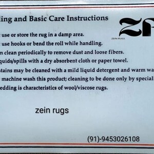 May include: A white card with black text detailing rug care instructions. The card includes advice on cleaning, storage, and maintenance. The brand name "zein rugs" is displayed, along with a logo and contact information.