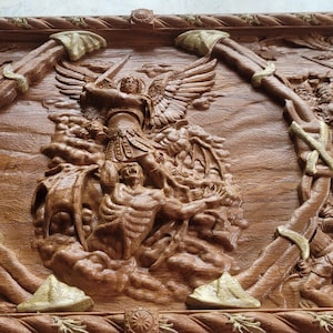 Könnte beinhalten: Detailliert geschnitztes Holzrelief, das eine Kampfszene mit Figuren in Rüstungen, Engeln und Pferden darstellt. Das Kunstwerk ist mit dekorativen Elementen umrahmt und hat eine warme braune Farbe.