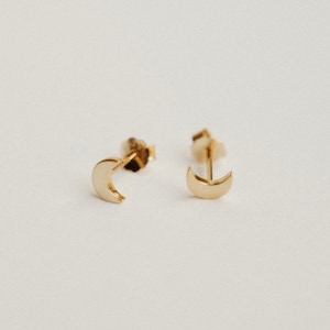May include: A pair of gold crescent moon stud earrings.